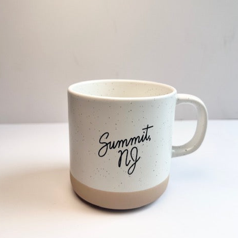 A two toned mug that reads "Jersey City" in black script. The bottom of the mug is tan and the rest of it is white with black specks.