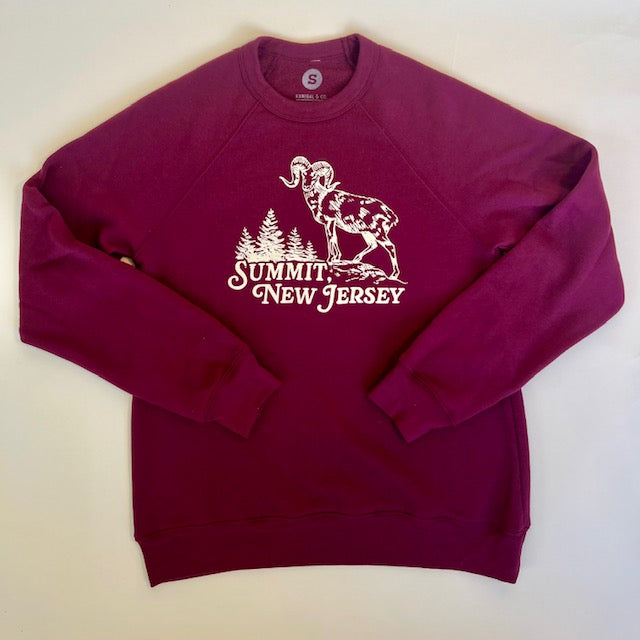 Maroon crewneck sweatshirt with a print of a ram standing atop a mountain with trees in the background. Under the print reads Summt, New Jersey.