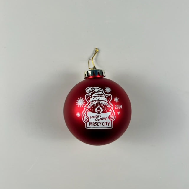 Red Christmas ornament with a racoon on it holding a sign that says "Season's Greetings Jersey City 2024" 